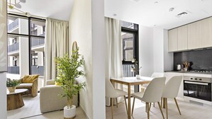 Een modern appartement met een eetgedeelte, keuken en een balkon met uitzicht op de buitenkant van het gebouw.