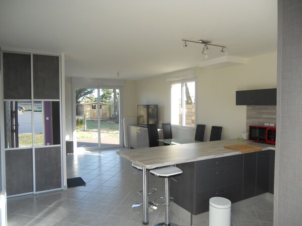 A modern kitchen with a large island, a refrigerator, and a microwave.