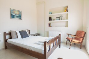Cozy bedroom with a comfortable bed, wooden chair, and a framed ocean view.