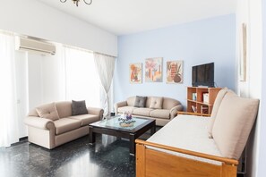 Relax in this stylish living room with a large sofa, TV, and bookshelf.