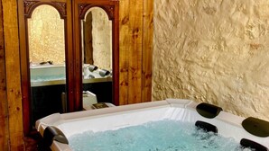 A wooden spa room with a hot tub, wooden beams, and a stone wall. - Maison et table d'hôtes le Camélia Blanc (Saint-Ciers-sur-Gironde)