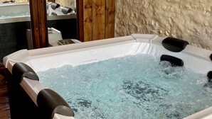 A hot tub with water, wooden walls, and a control panel. - Maison et table d'hôtes le Camélia Blanc (Saint-Ciers-sur-Gironde)