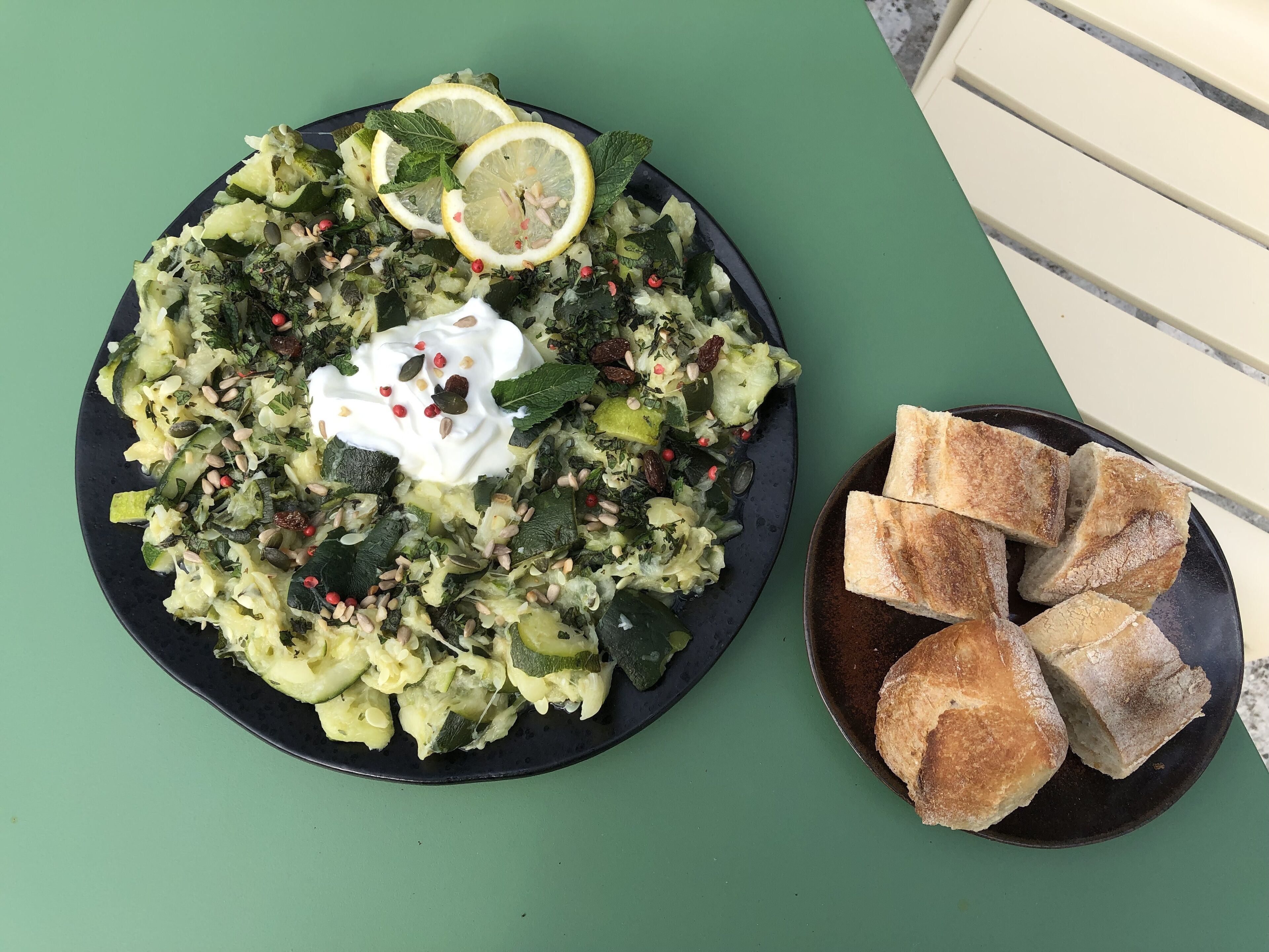 Un plato de comida con una guarnición de pan sobre una mesa verde.
