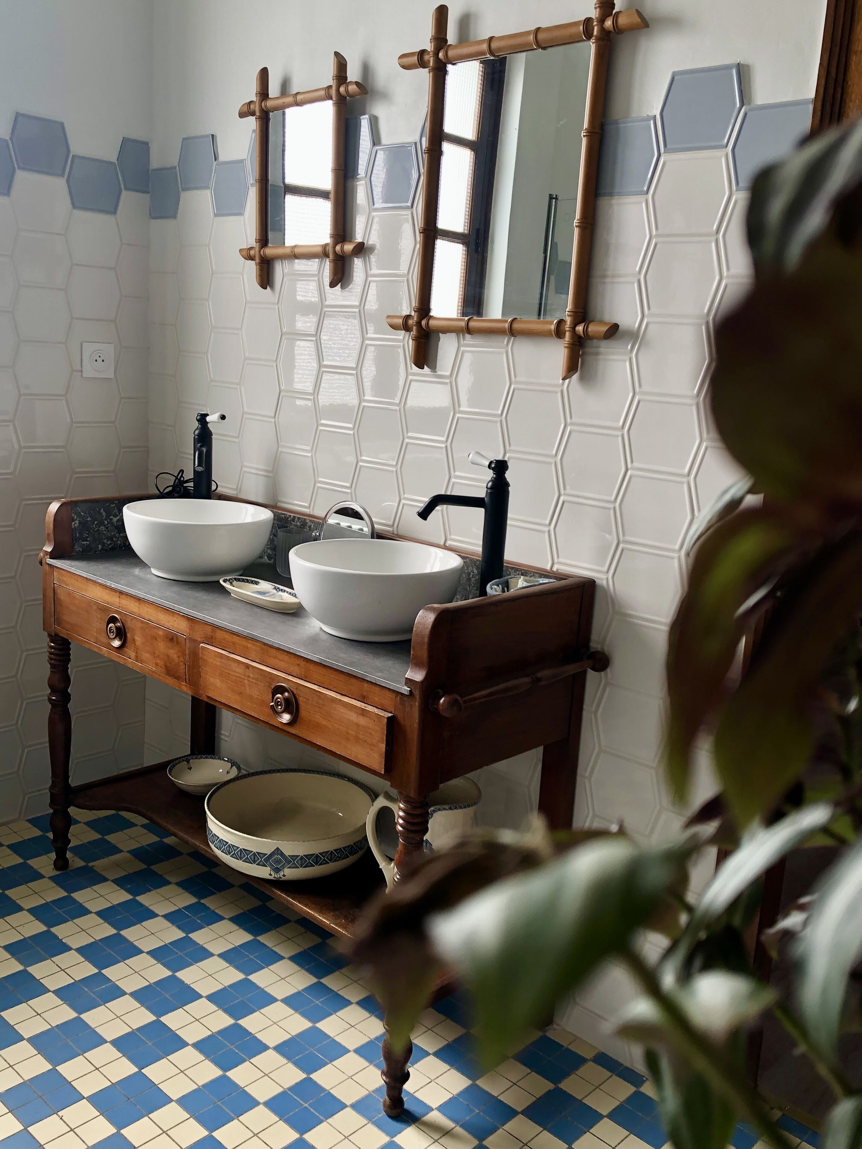 A bathroom with a checkered floor, a wooden vanity with a sink, and a mirror above.