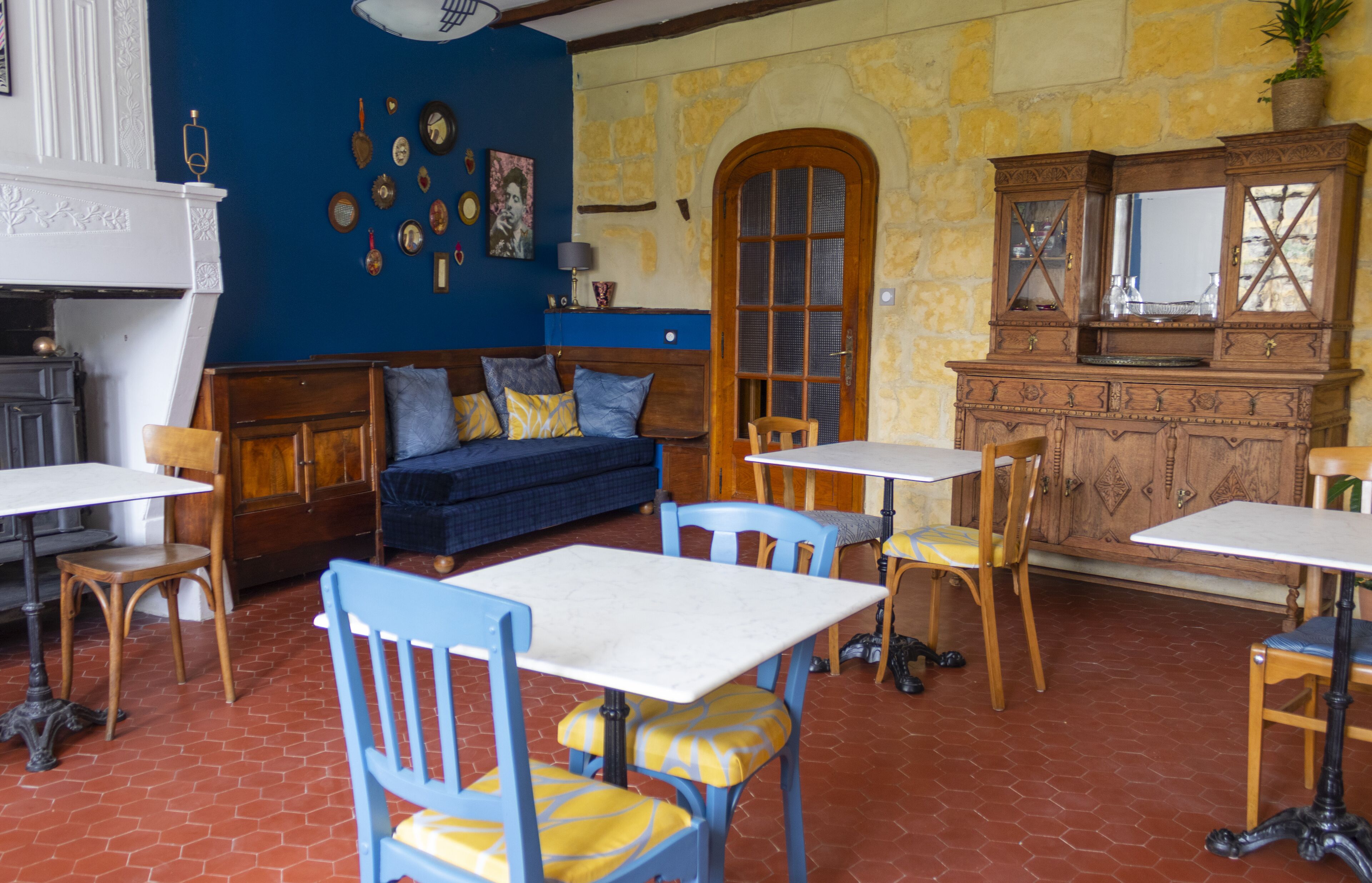 A cozy room with a blue sofa, wooden chairs, a white table, and a wooden cabinet with glass doors.