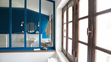 A bathroom with a large mirror, a sink, and a window.