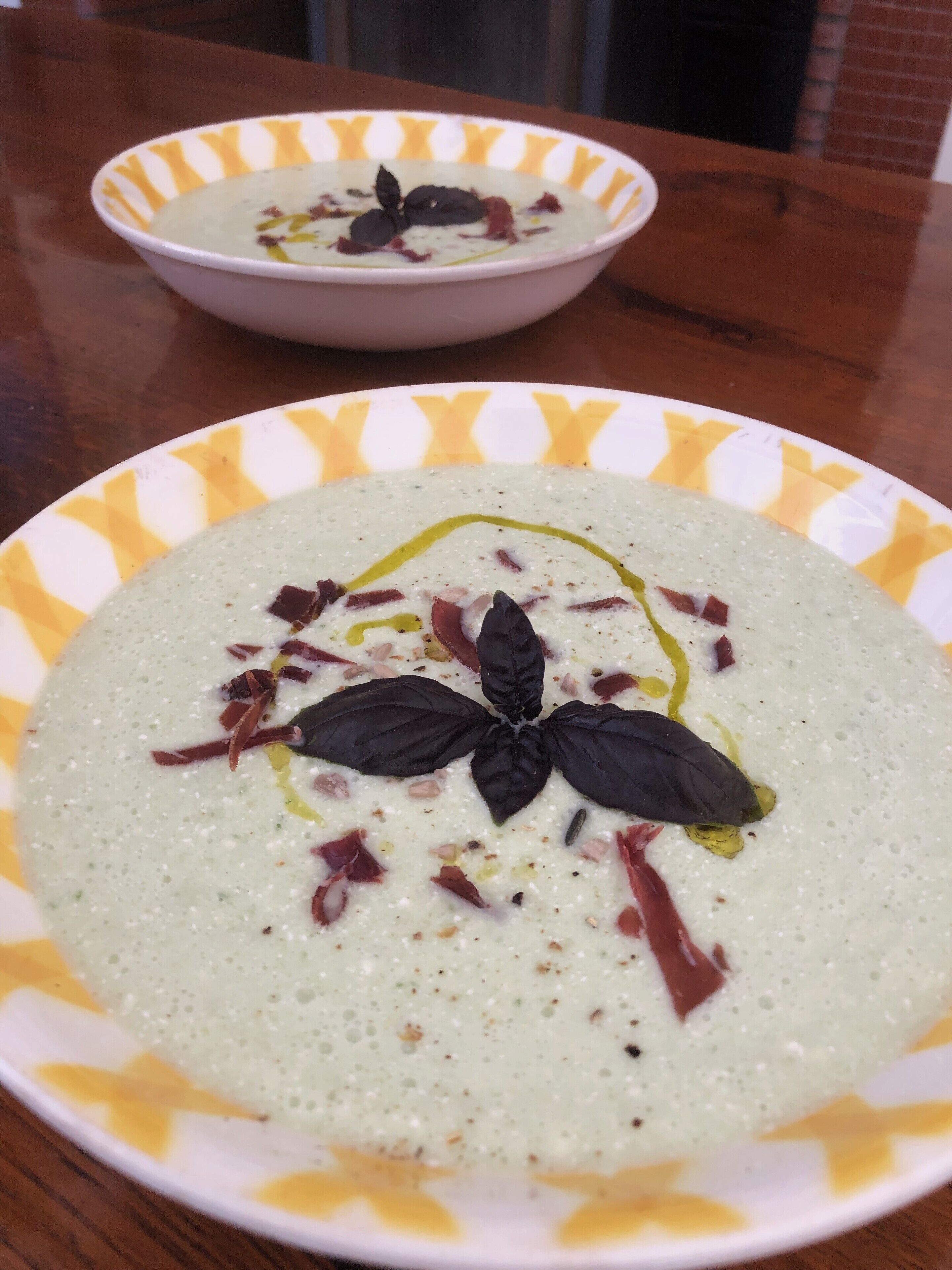 Two bowls of soup on a wooden table.