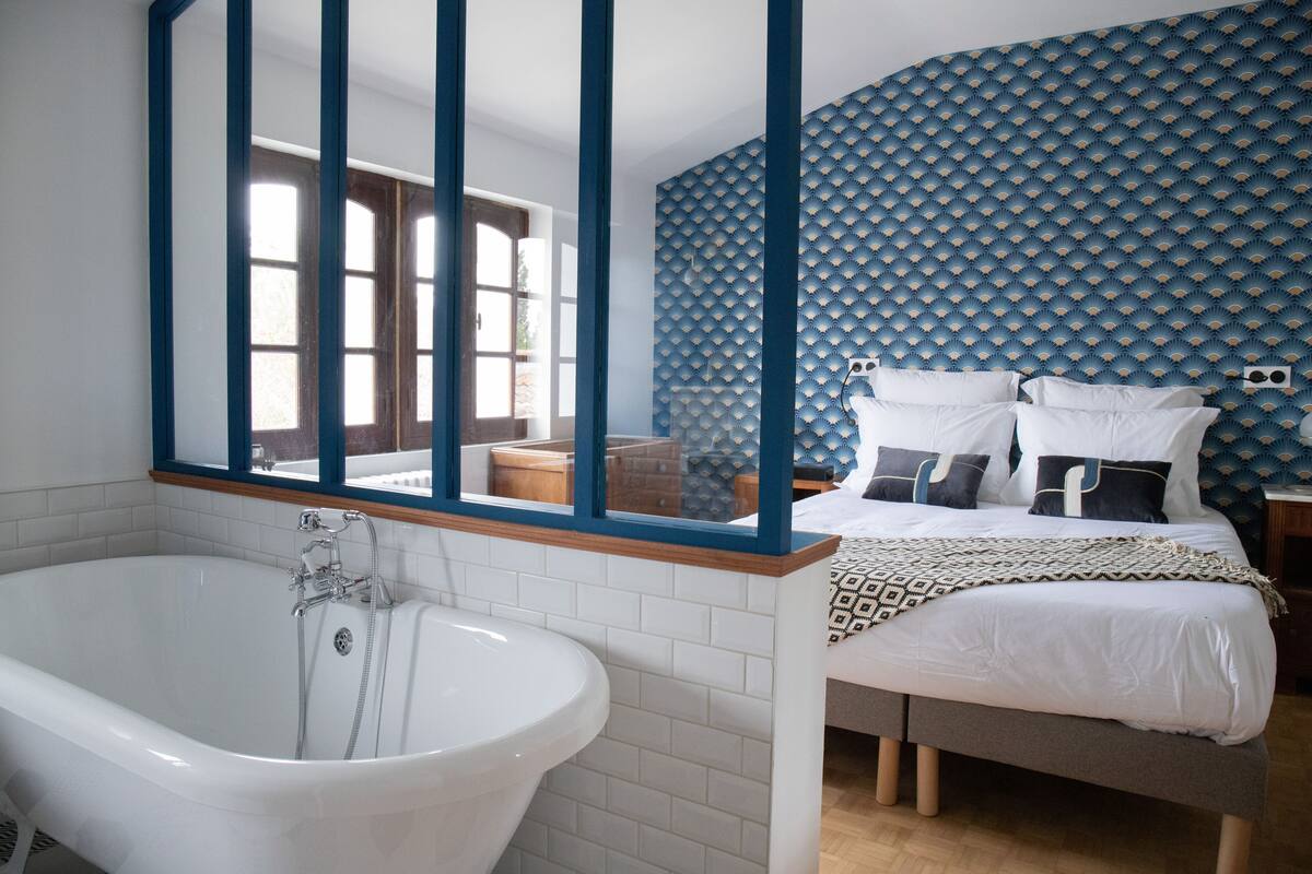 A bathroom with a freestanding bathtub, a large mirror, and a window with a view of the outside.