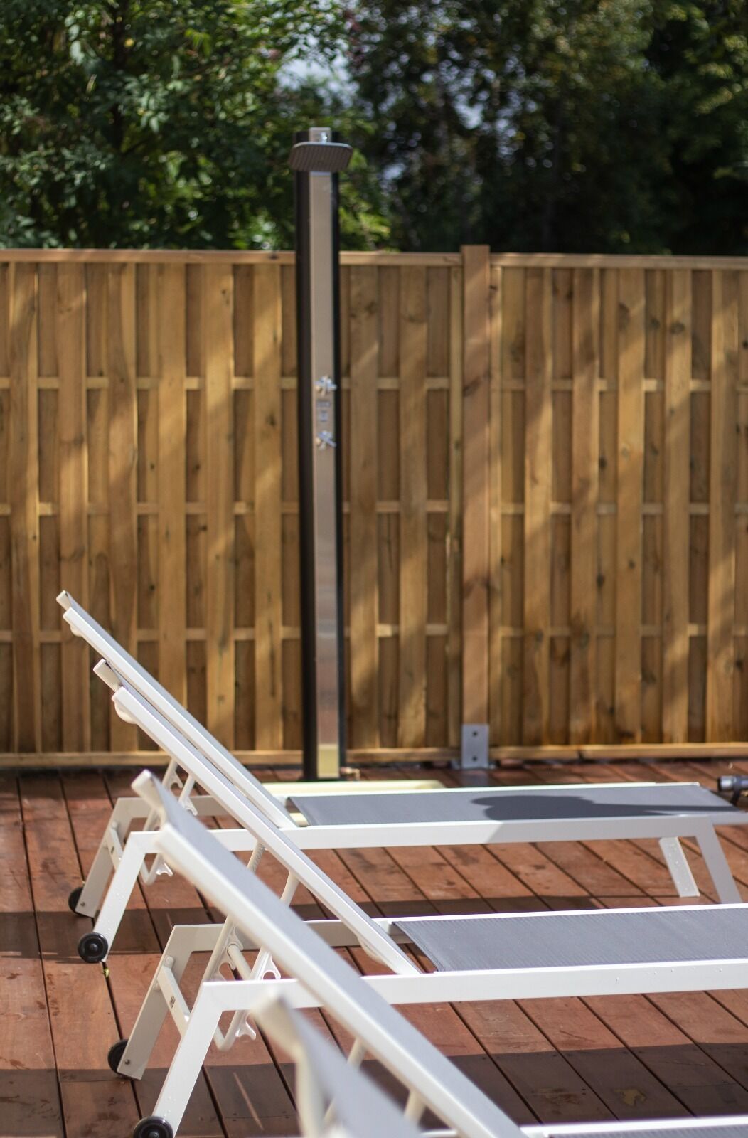 A wooden deck with white lounge chairs and a vertical pole.