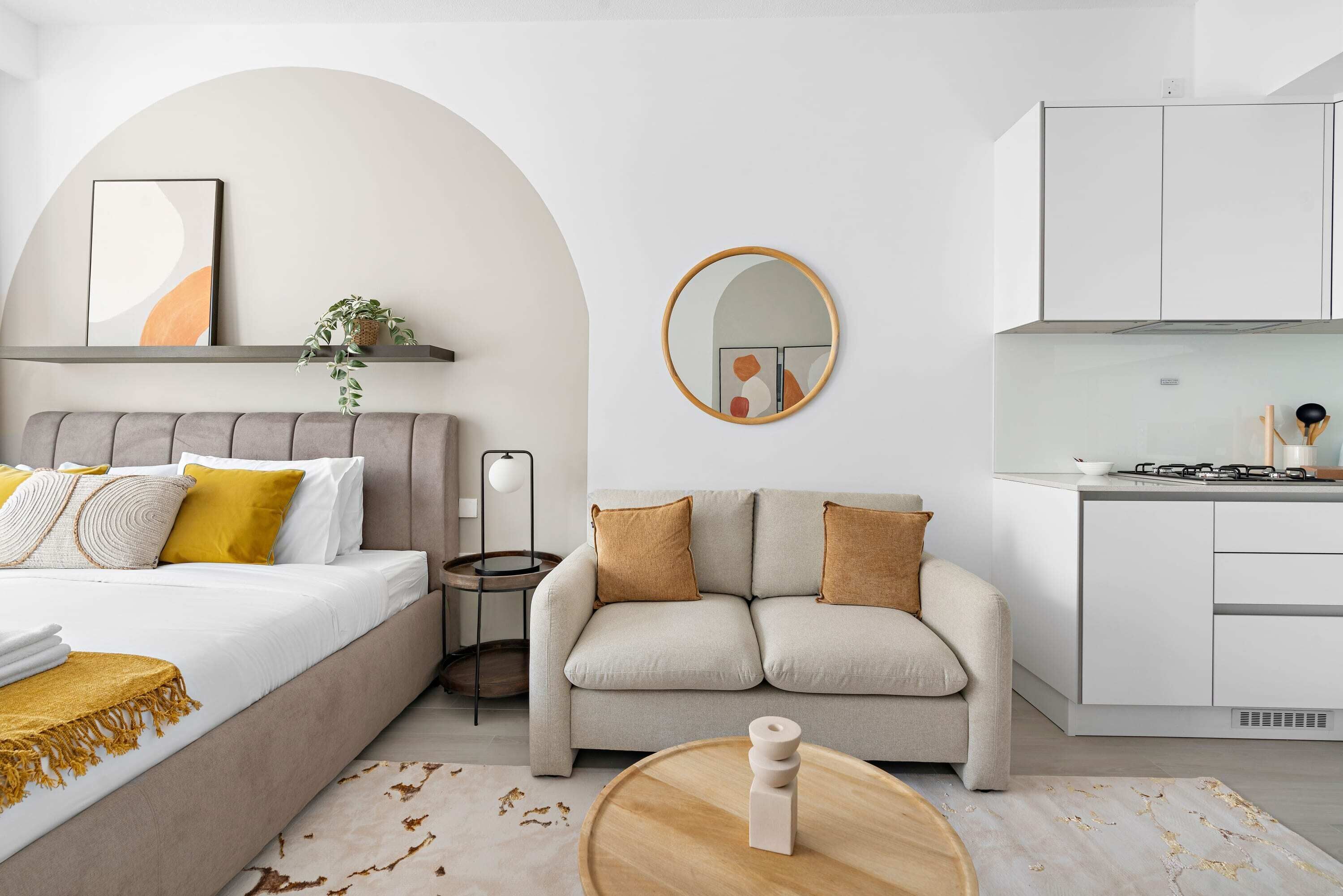 A modern, minimalist bedroom with a large bed, a sofa, and a small side table.