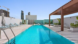 Ein Pool auf dem Dach mit Liegestühlen und einer Pergola.
