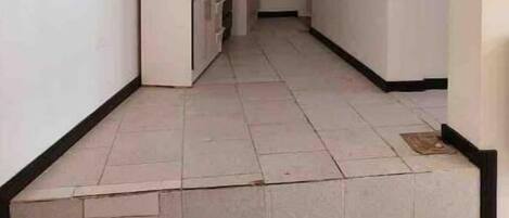 Un pasillo estrecho con una zona de cocina, que incluye un refrigerador y armarios.