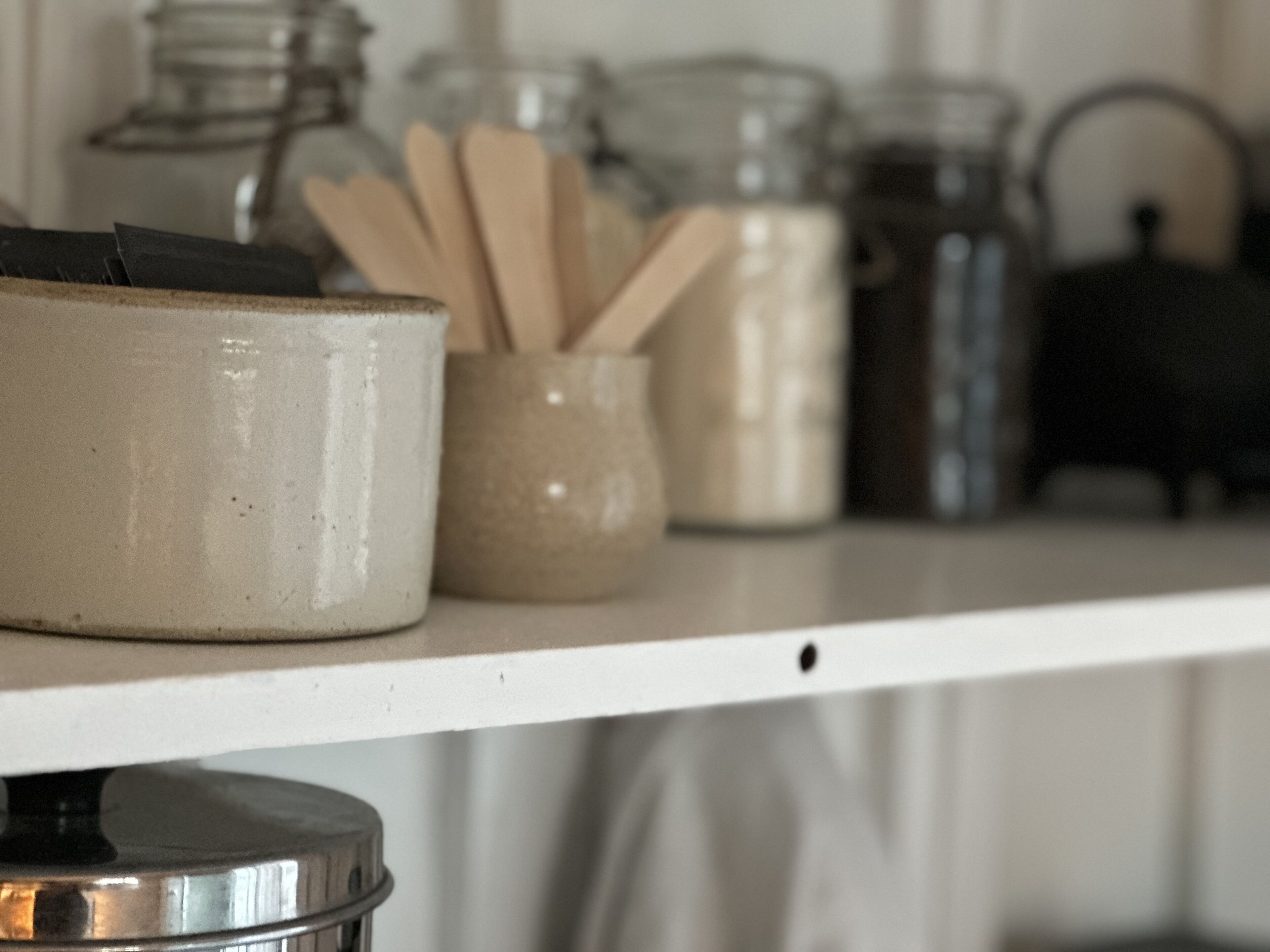 A kitchen shelf with various containers and utensils.