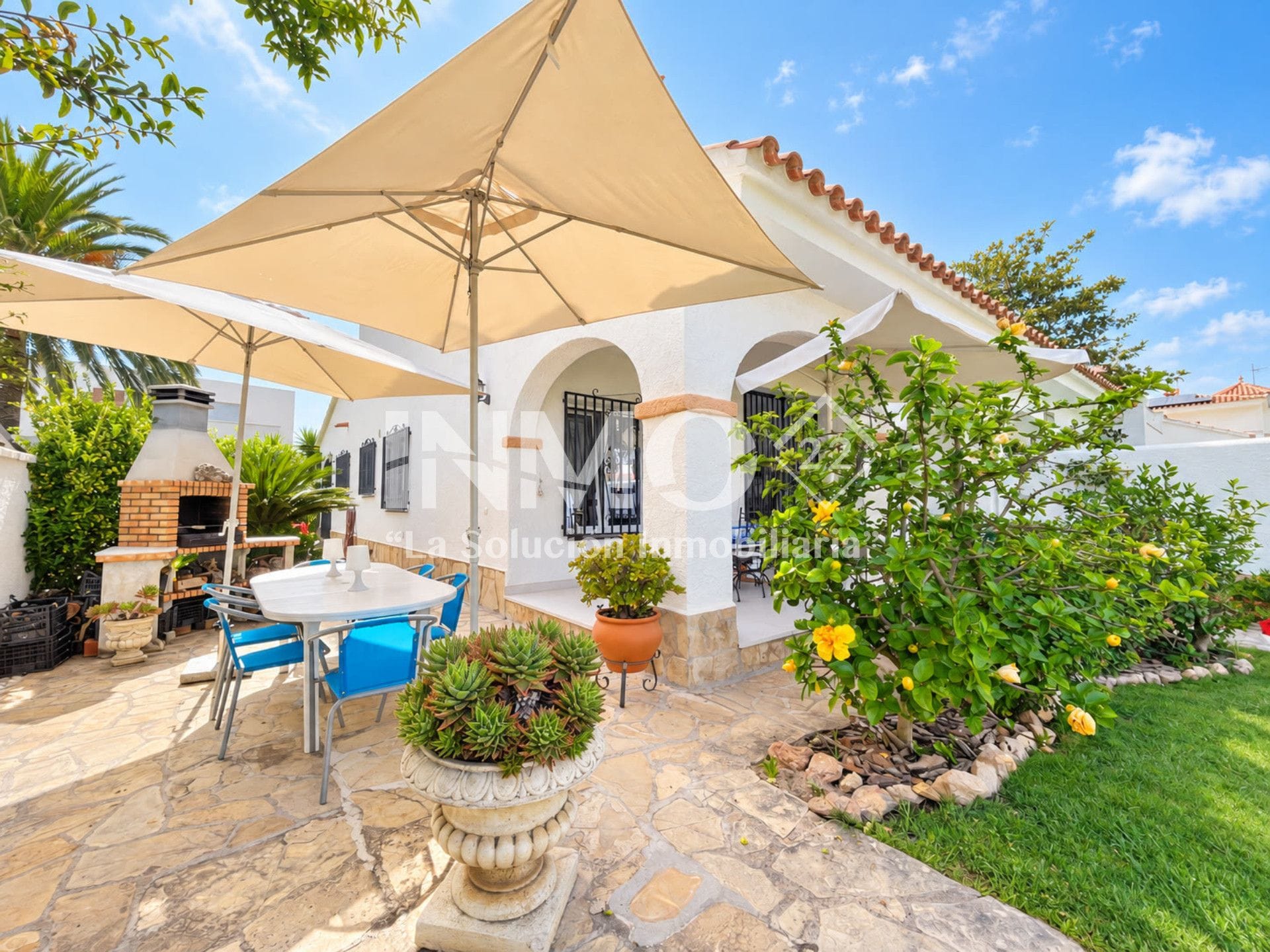 A patio with a table and chairs, a barbecue grill, and a large umbrella.