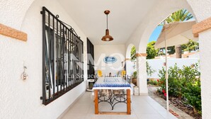 A covered patio area with a dining table and chairs, a black metal gate, and a hanging pendant light.