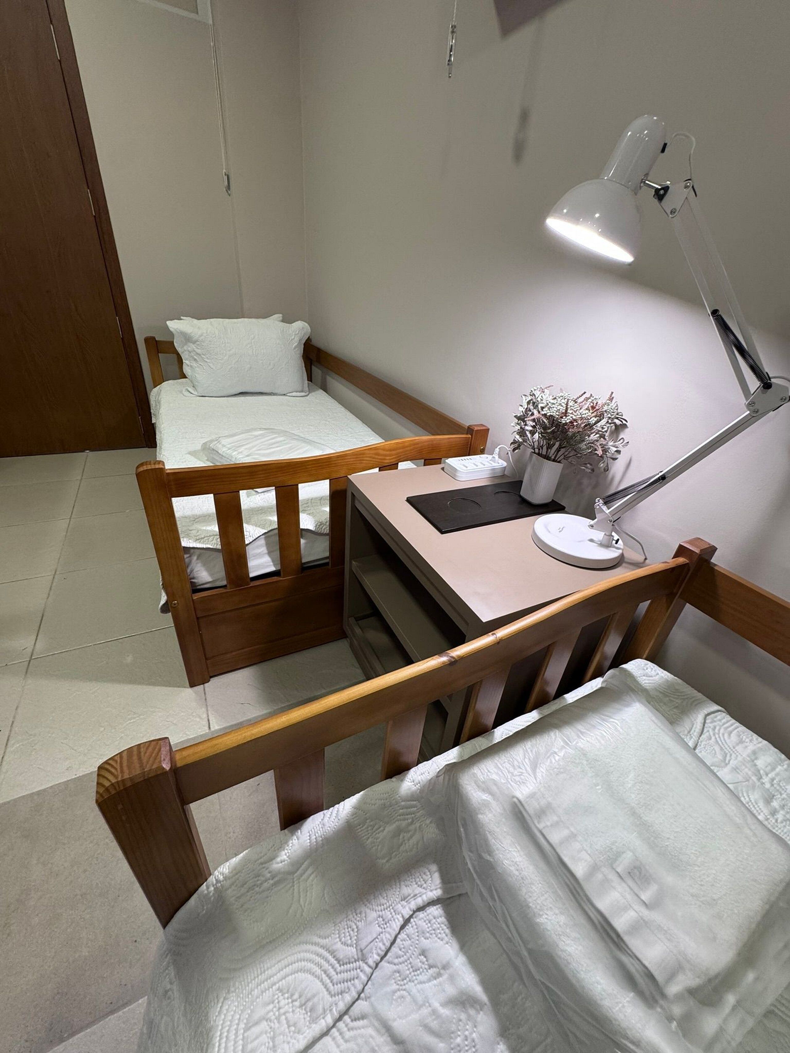 A small, neatly arranged room with a bed, a desk, and a chair.