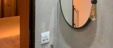 A bathroom with a wooden door, a sink with a mirror, and a light fixture.