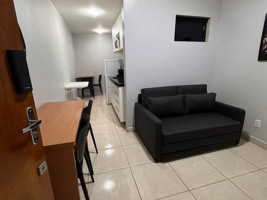 A compact living space with a kitchenette, a sofa, a dining area, and a door with a lock.