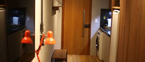 A narrow kitchen with wooden cabinets, a countertop, a sink, and a microwave.