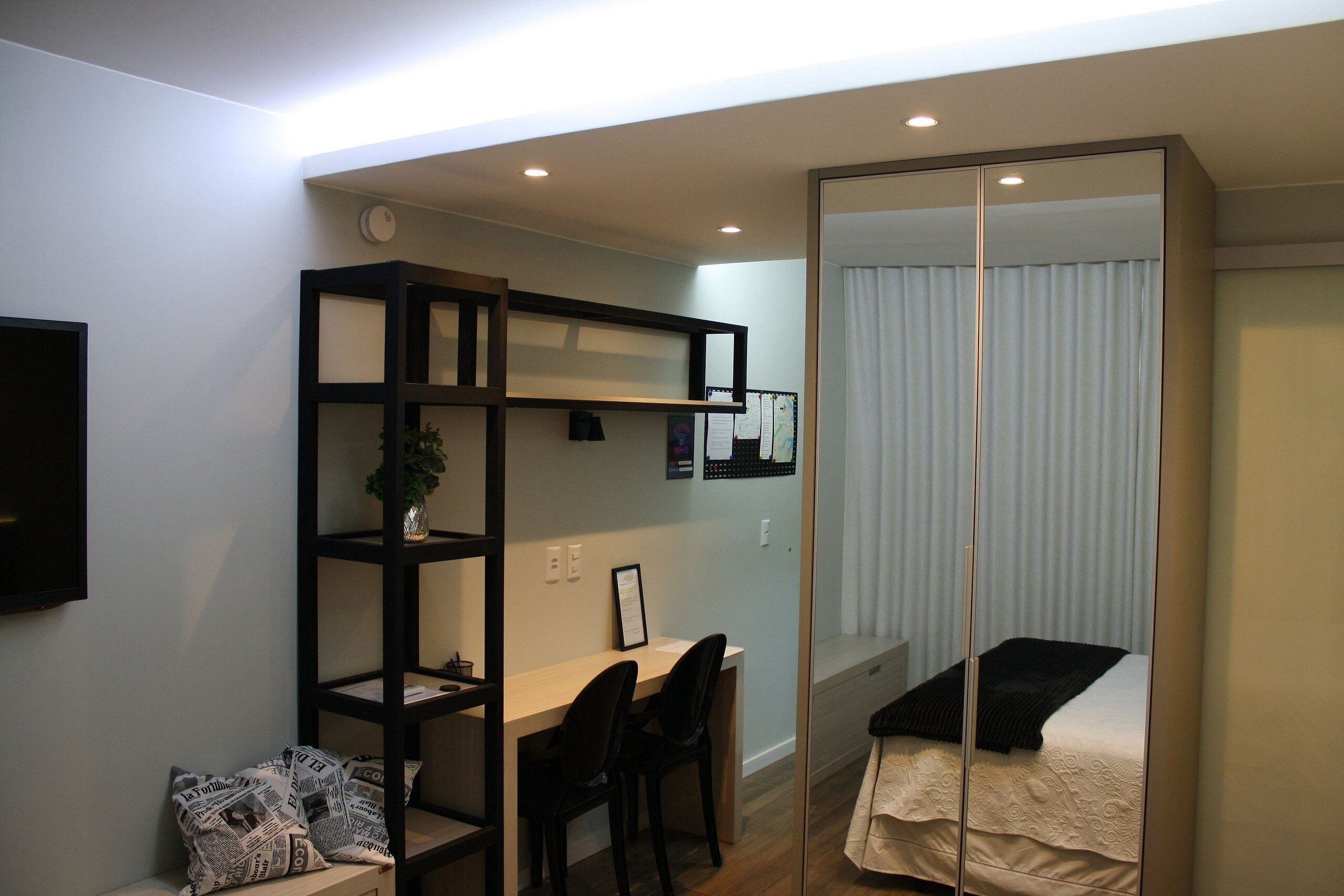 Un dormitorio pequeño con cama, escritorio y estantería.