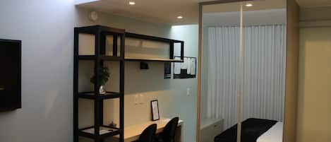 Un dormitorio pequeño con cama, escritorio y estantería.