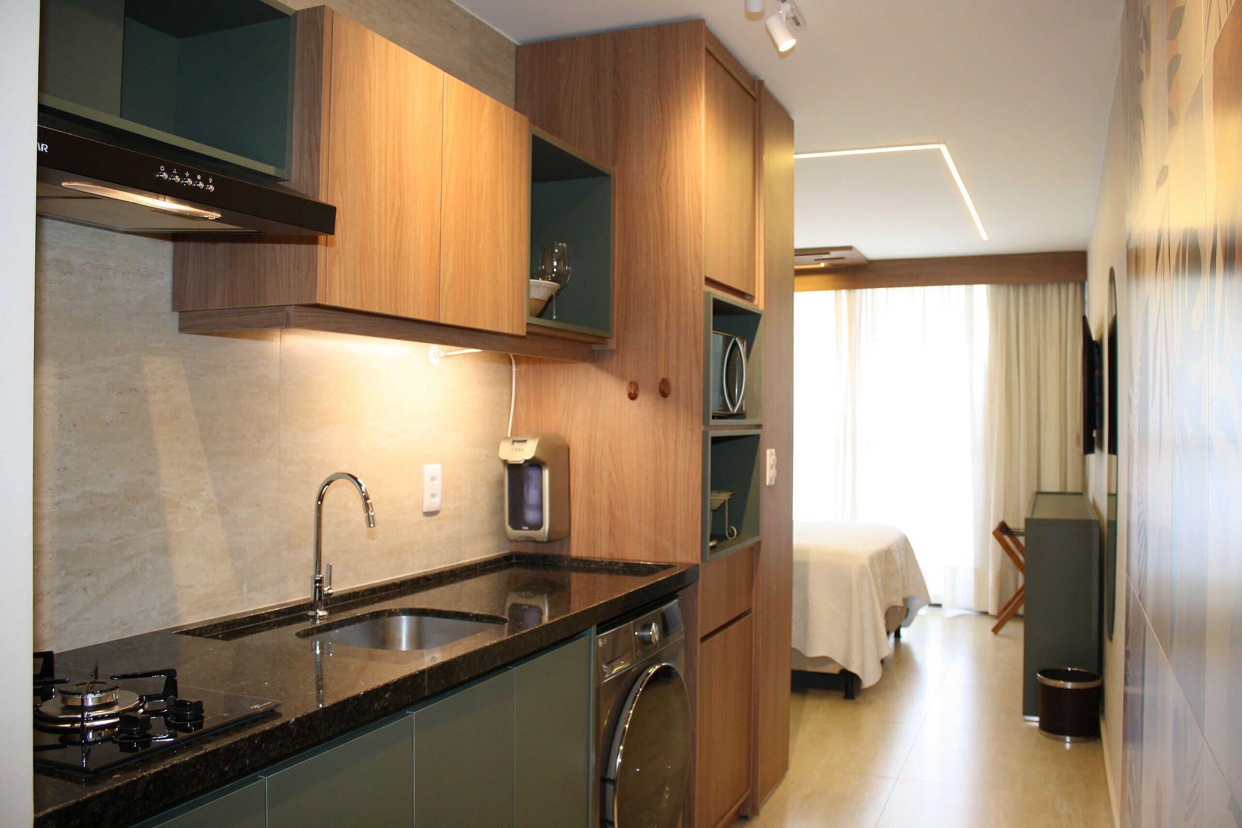 A modern kitchen with a built-in stove, sink, and dishwasher, wooden cabinets, and a dining area with a table and chairs.