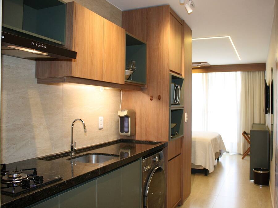 A modern kitchen with a built-in stove, sink, and dishwasher, wooden cabinets, and a dining area with a table and chairs.