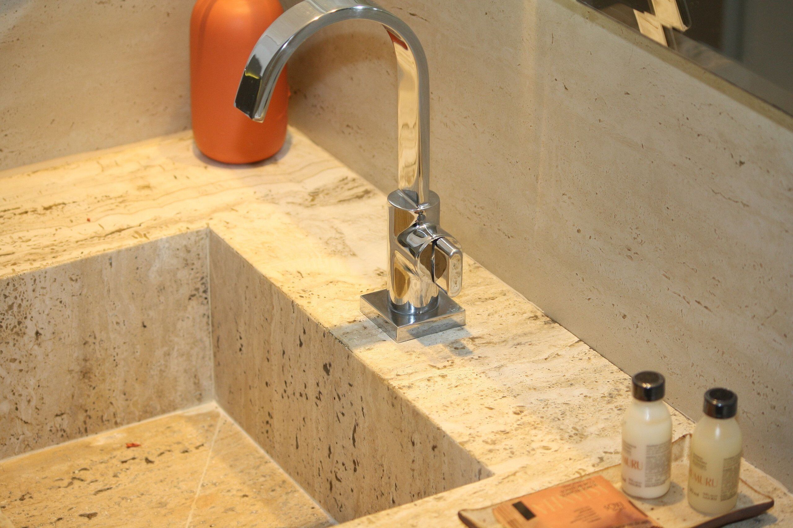A bathroom sink with a chrome faucet, a soap dispenser, and a razor holder.