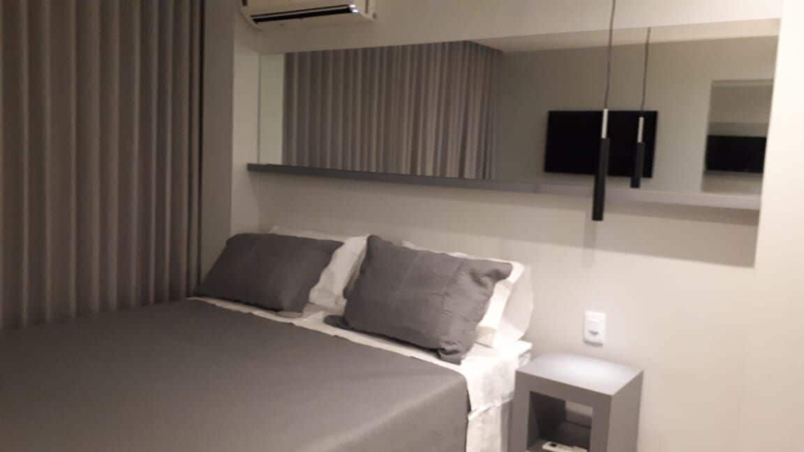 Une chambre d’hôtel moderne équipée d’un lit, d’une table de chevet, d’une télévision et d’une grande fenêtre avec des rideaux.