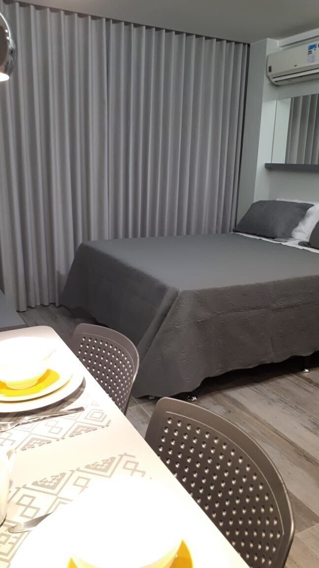 Una camera d'albergo con un letto, un tavolo e sedie, e un condizionatore.
