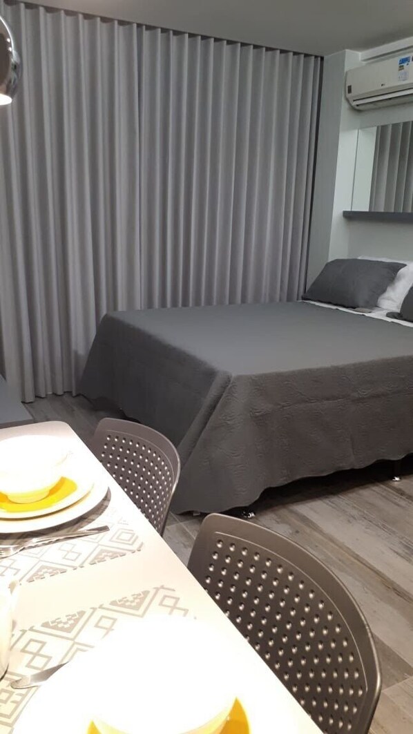 A hotel room with a bed, a table with chairs, and an air conditioning unit. - Flats Asa Norte CLN 110 bloco B (Brasília)
