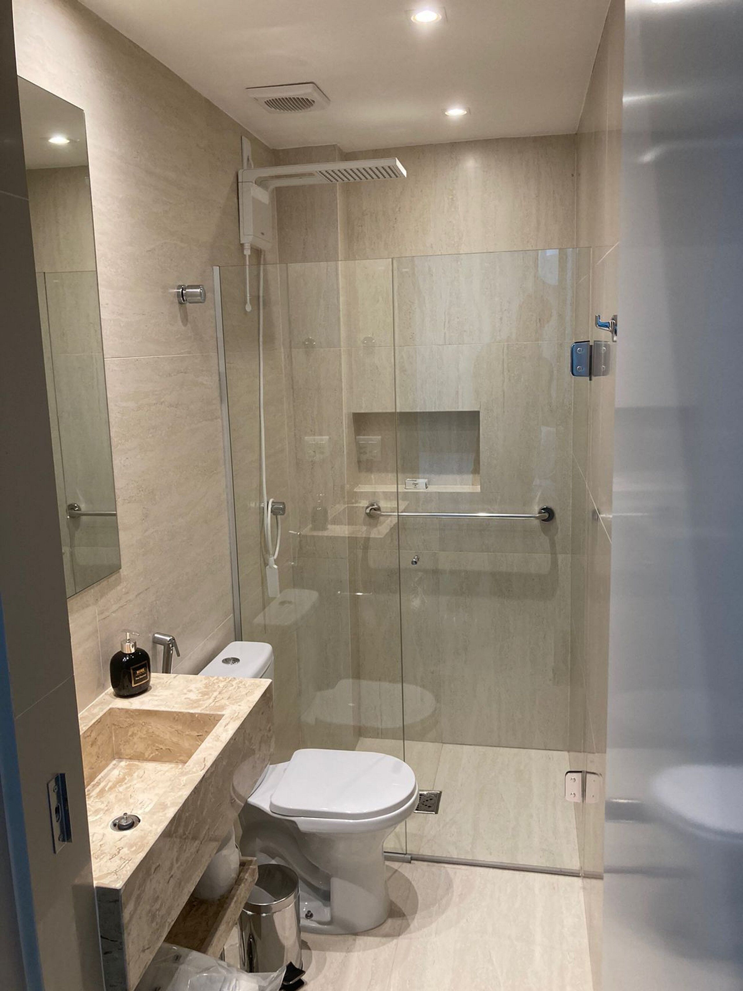 Un baño moderno con cabina de ducha de vidrio, lavamanos de mármol y un inodoro.
