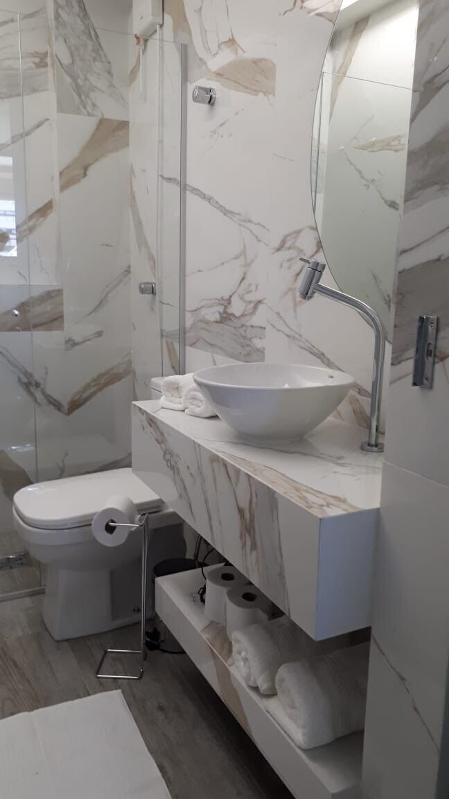 A bathroom with a toilet, a sink, and a mirror.