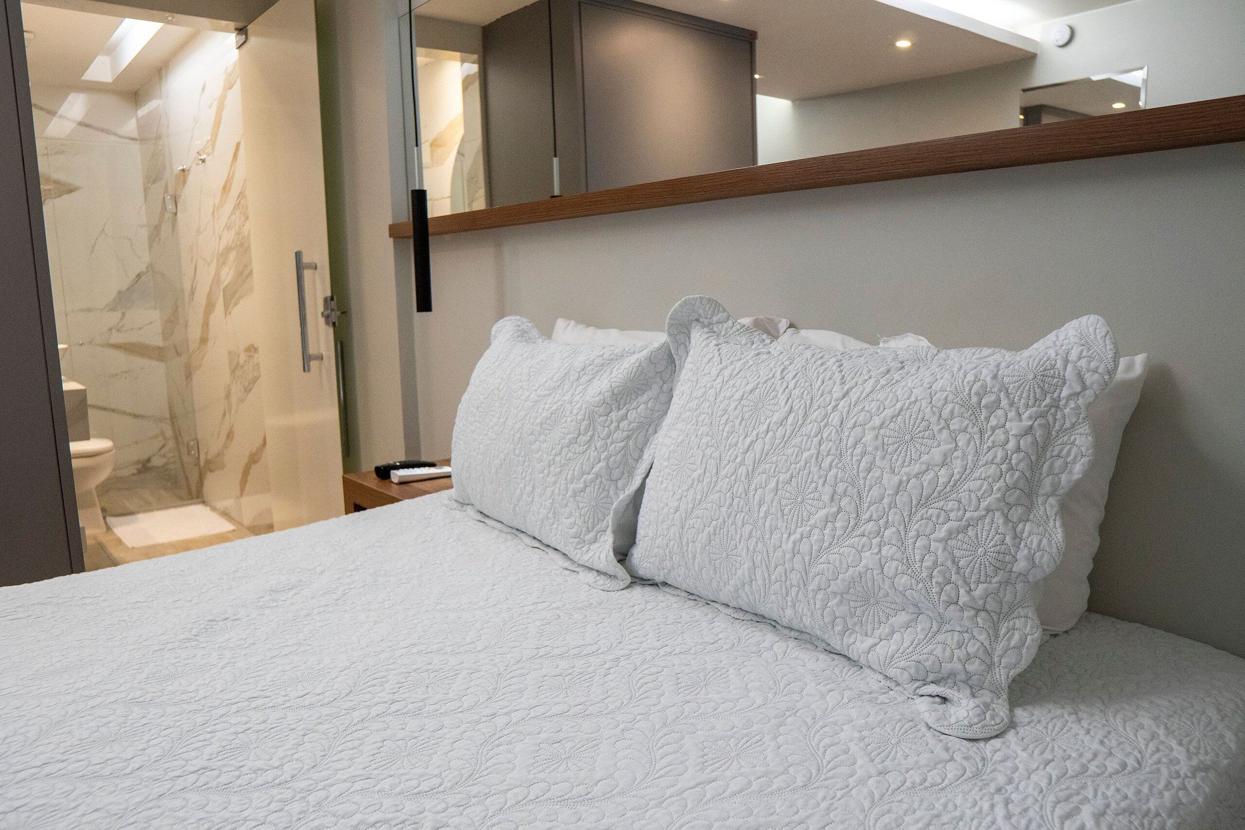 Een hotelkamer met een bed, een houten hoofdeinde, een spiegel en een badkamer die door een open deur zichtbaar is.