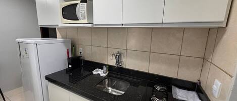 A compact kitchen with a microwave, sink, and stove.