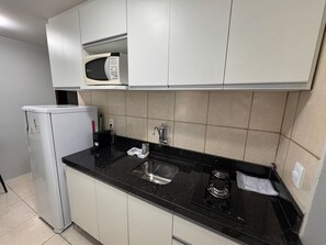 A compact kitchen with a microwave, sink, and stove. - Flats Asa Norte CLN 110 bloco B (Brasília)