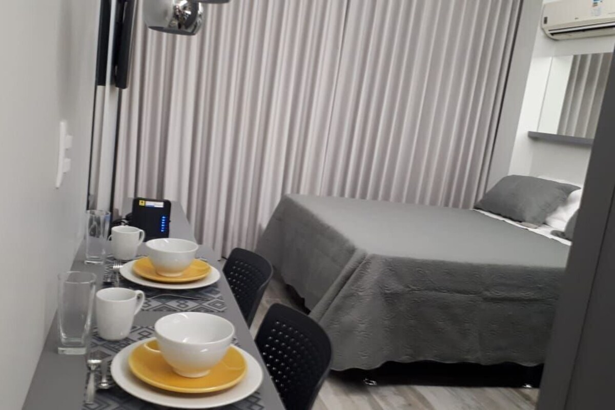 A hotel room with a bed, a dining table with chairs, and a small kitchenette area.