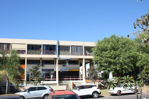 A multi-story building with balconies, a sign for 'Salão Ben Star', and parked cars.