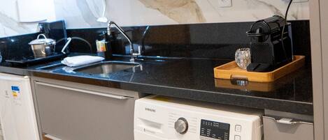 Une cuisine compacte équipée d’un four à micro-ondes, d’une machine à café et d’un lave-linge.