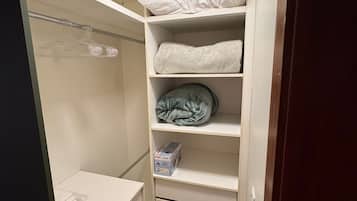 Un vestidor con repisas, barra para colgar ropa y un banco de almacenamiento.