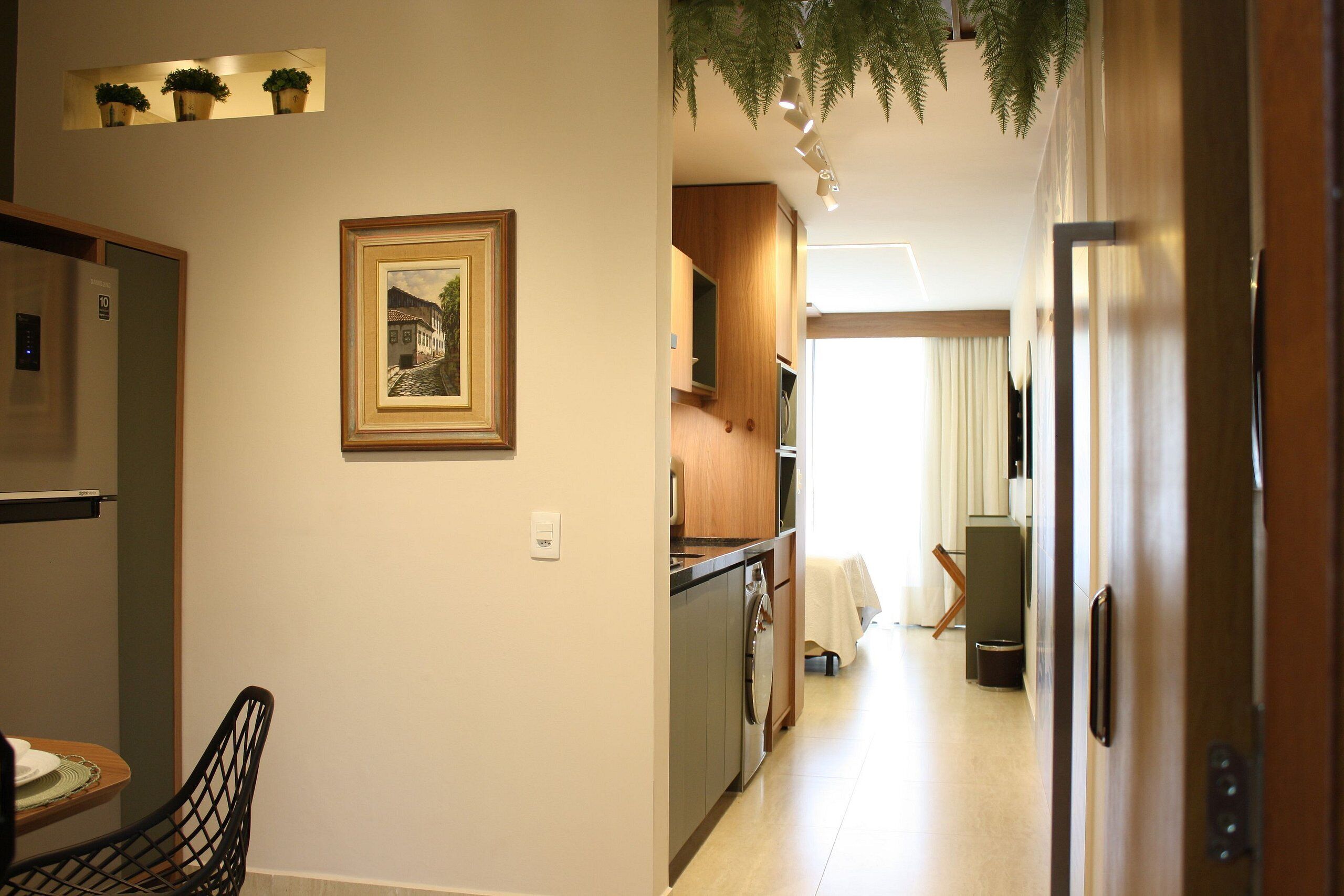 A kitchen with wooden cabinets, a refrigerator, and a dining area with a chair and table.