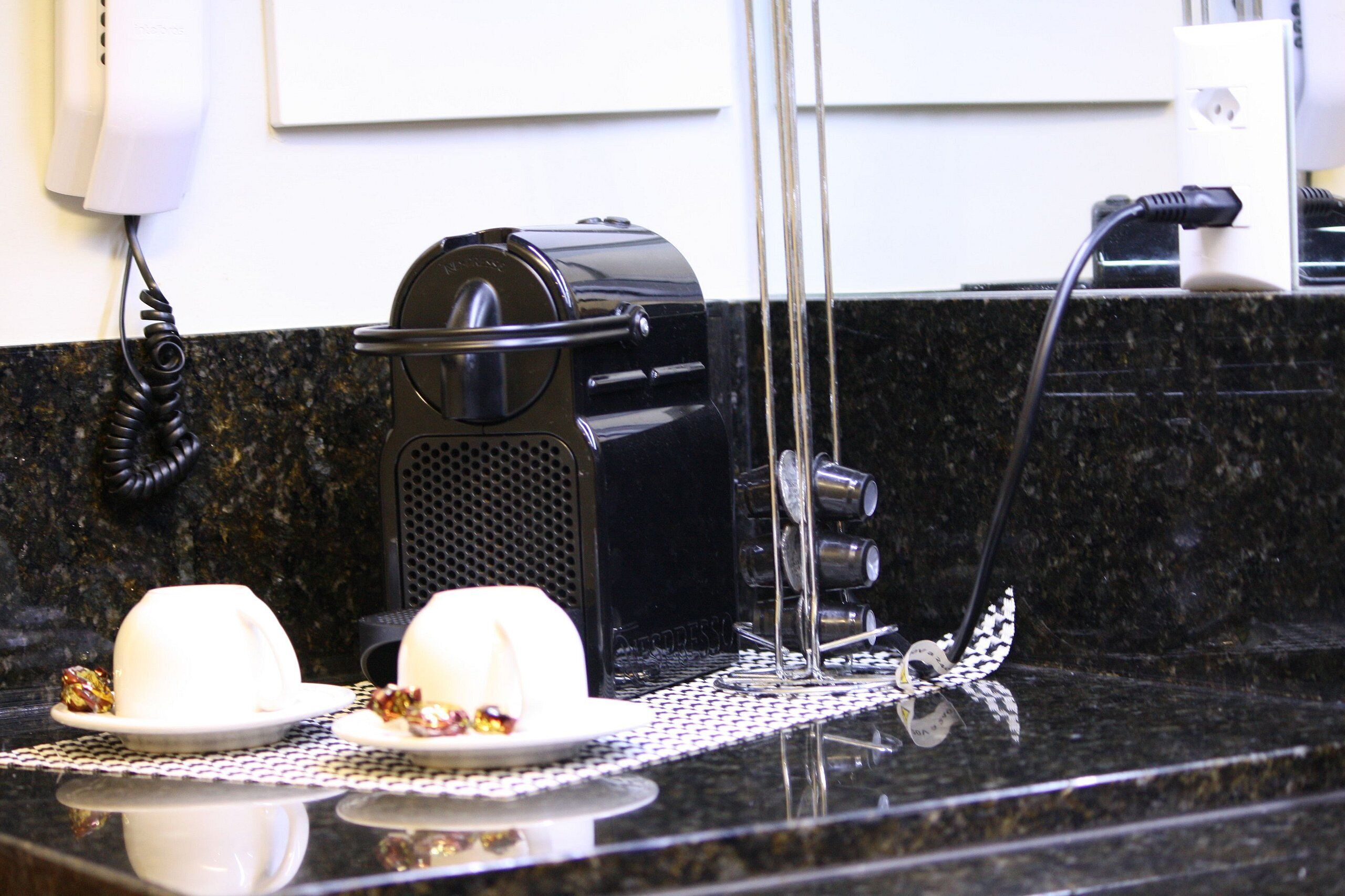 A kitchen counter with a coffee maker, a phone, and a power outlet.