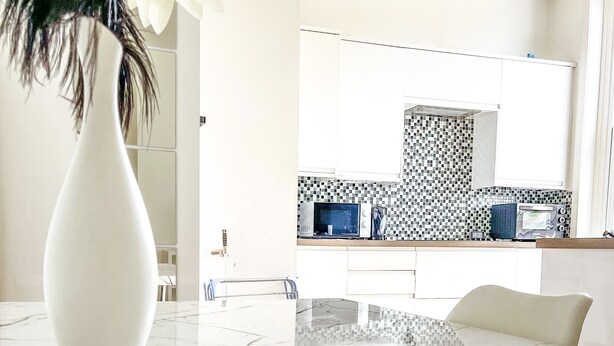 Un baño moderno con lavamanos de mármol blanco, un espejo grande y un salpicadero de azulejos.