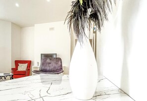Experience a serene atmosphere in this stylish space with a large vase, a marble-topped table, and comfortable seating.