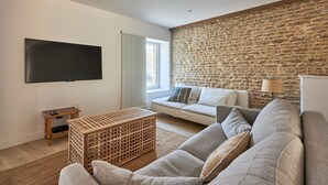 Una sala de estar moderna con una pared de piedra, un televisor de pantalla plana grande, un sofá y una mesa de centro de madera.