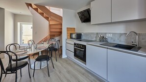 Una cocina moderna con armarios blancos, horno empotrado, microondas y pileta de acero inoxidable.