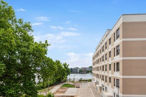 A modern building with a river view, a well-maintained lawn, and a clear sky. - Habyt Berlin Waterfront (Berlin)