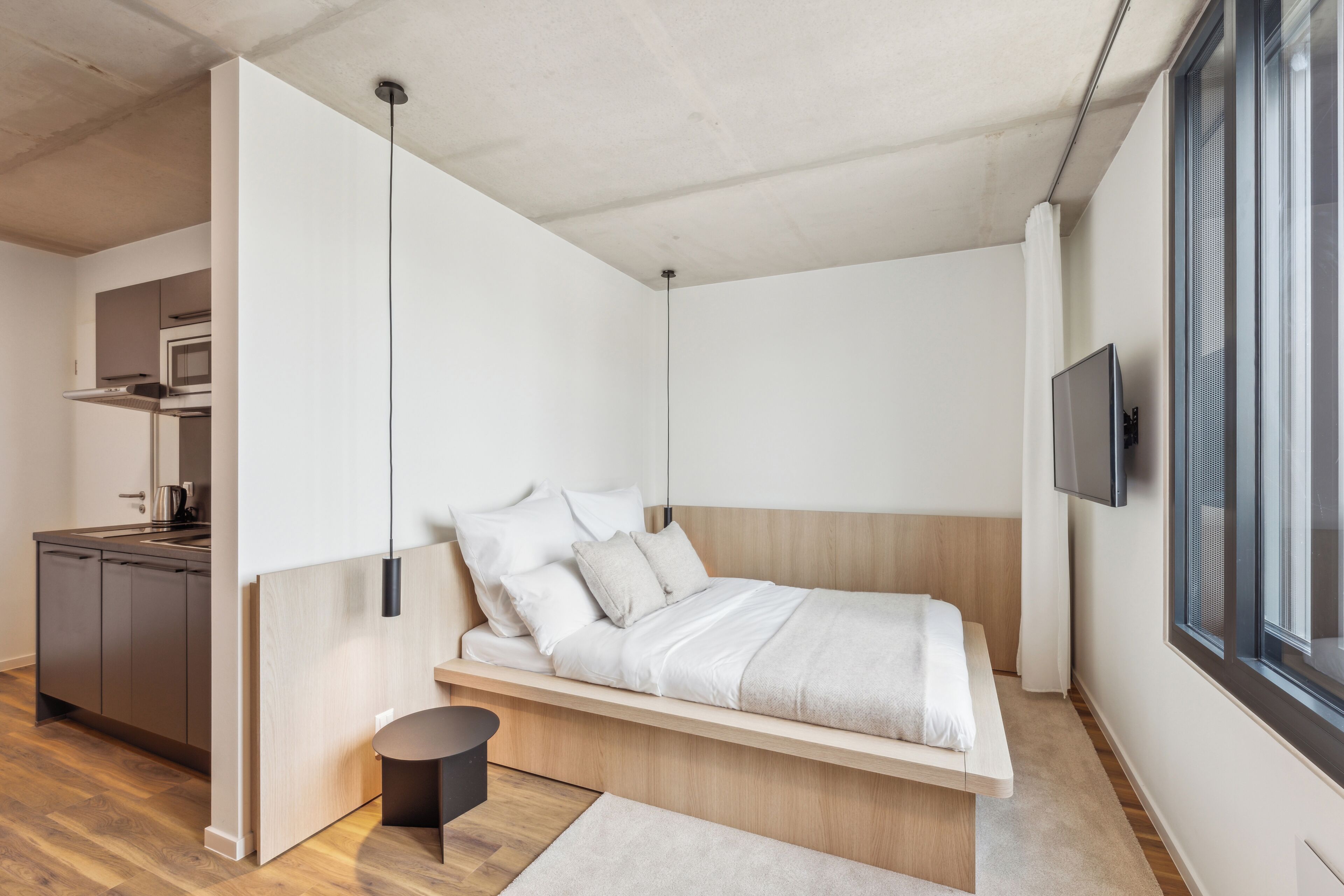 A modern bedroom with a bed, bedside table, and a TV.