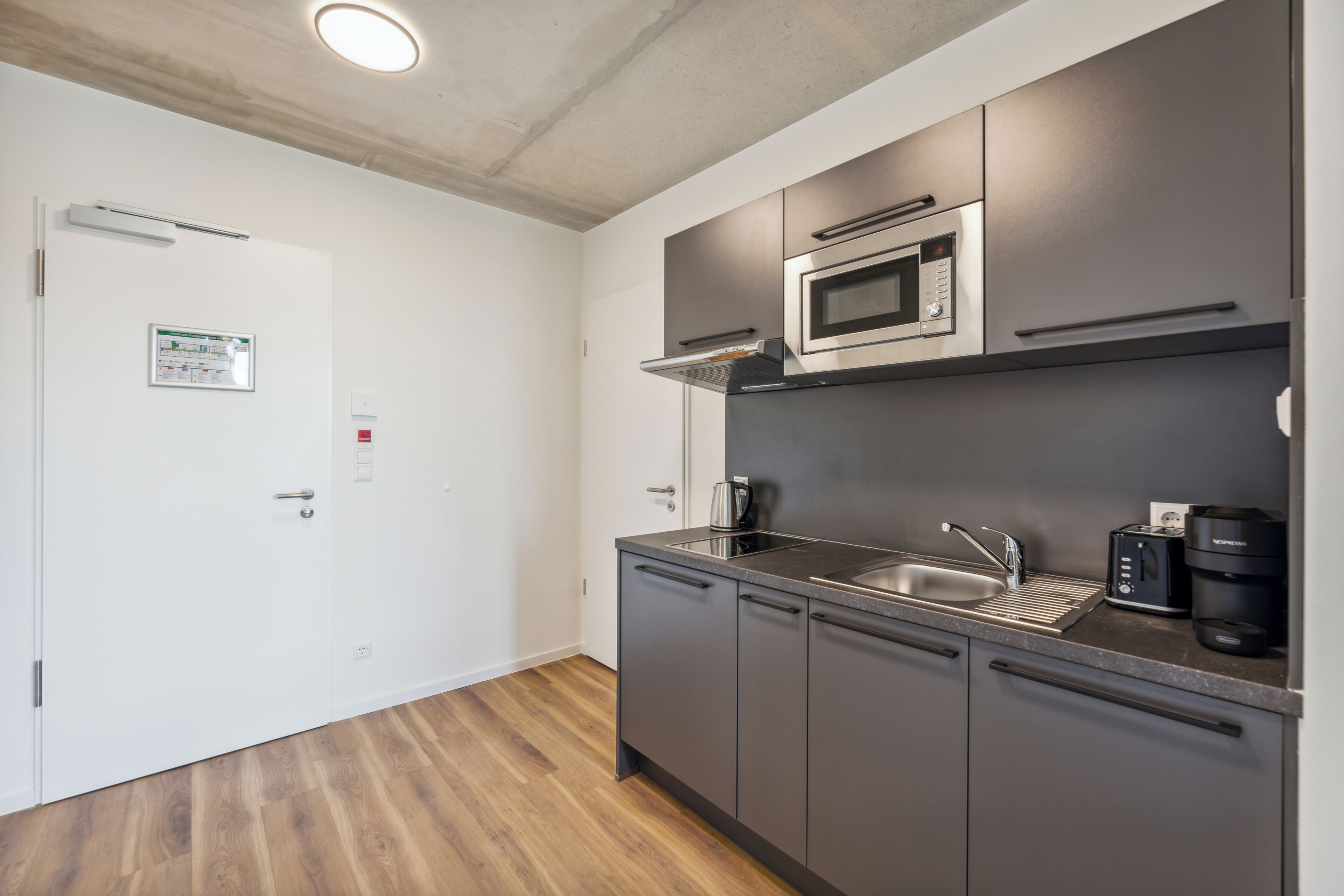 A modern kitchen with a microwave, coffee maker, and sink.