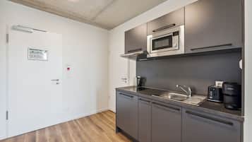 A modern kitchen with a microwave, coffee maker, and sink.